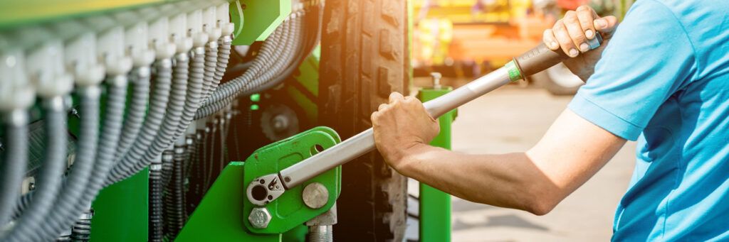 Técnico ajustando equipamento agrícola com chave de torque