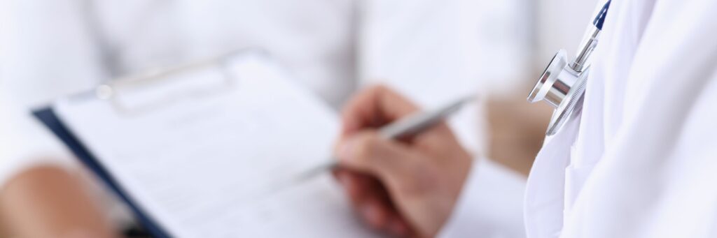Profissional da saúde com caneta na mão preenchendo atestado médico