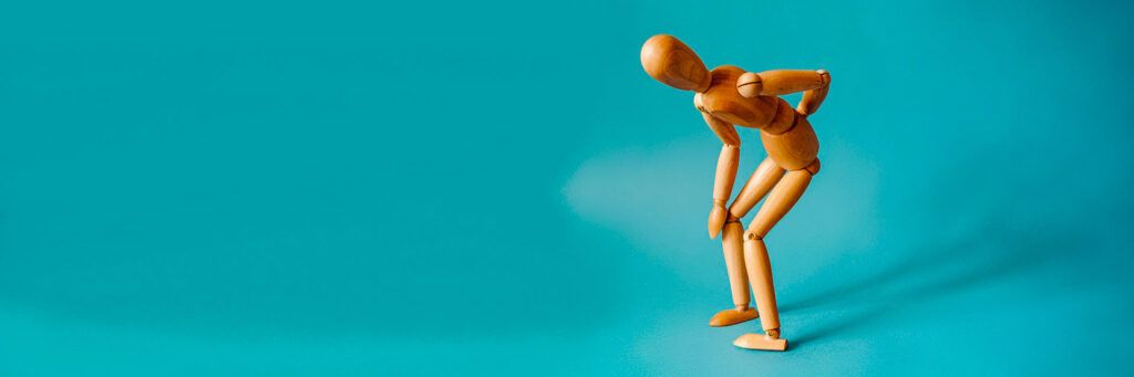 Boneco de madeira curvado com as mãos nas costas sobre fundo azul