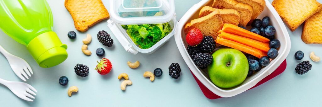 Marmita saudável com frutas, legumes e castanhas espalhados na mesa