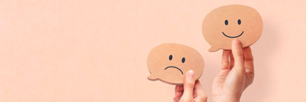 Duas pessoas erguendo duas placas, uma sorrindo e outra triste