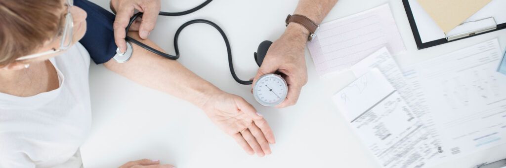 Profissional medindo pressão arterial simbolizando saúde preventiva e cuidados médicos regulares.