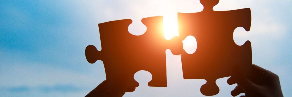 Peças de quebra-cabeça encaixando simbolizando integração, solução e trabalho em equipe.