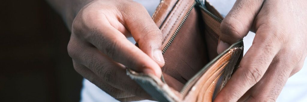 Pessoa abrindo carteira vazia simbolizando finanças pessoais, economia e segurança financeira.
