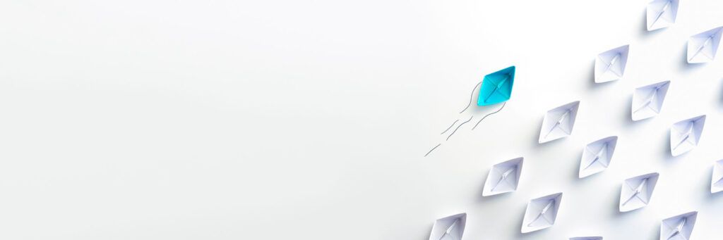 Barco de papel na cor azul separado de outros barcos na cor branca