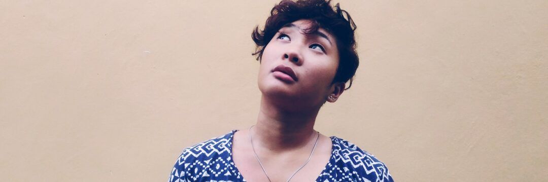 Pessoa pensativa olhando para cima simbolizando reflexão, autoconhecimento e saúde mental.